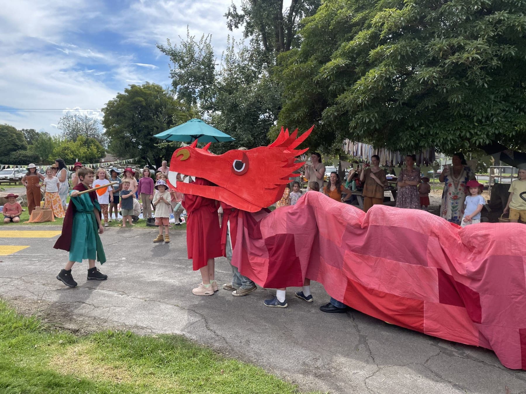 A red dragon puppet paraded by costumed children at a Wild Cherry seasonal festival