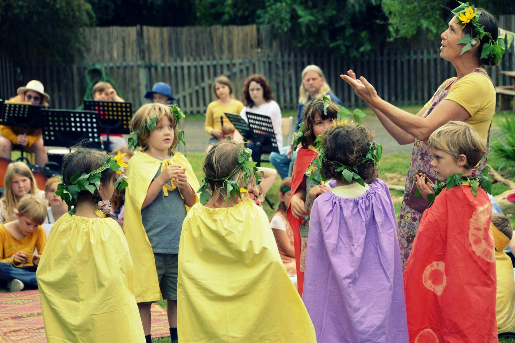 Children in seasonal robes and leaf crowns at a Wild Cherry community celebration