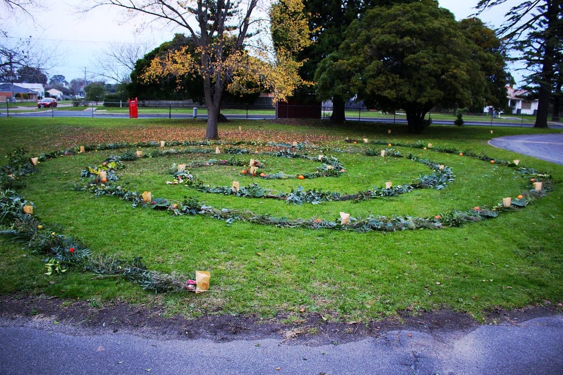 A spiral of candlelit lanterns laid on grass at the Winter Festival