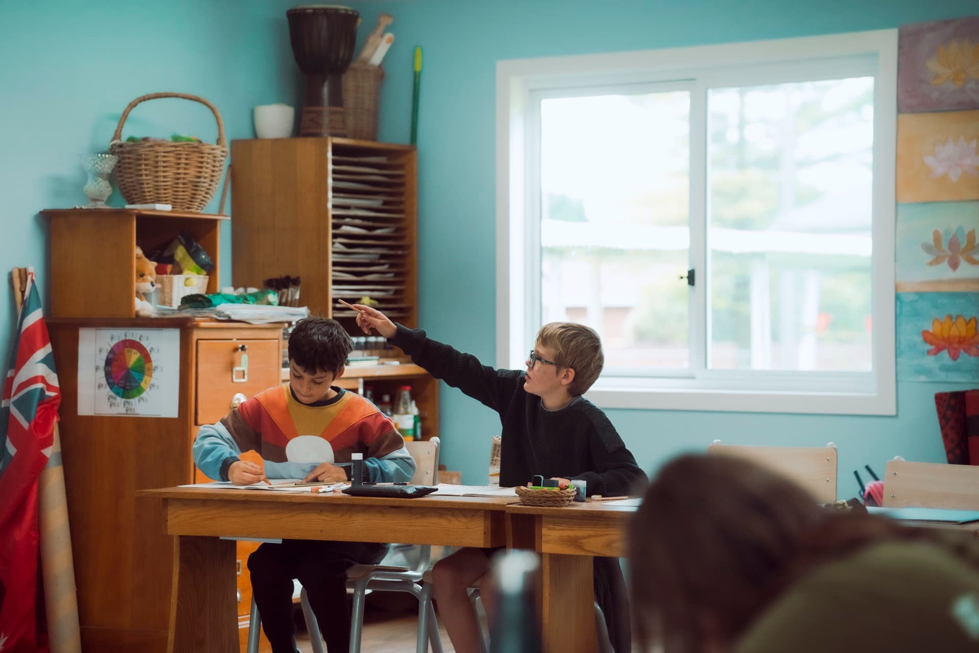 A class teacher working with students at a classroom table